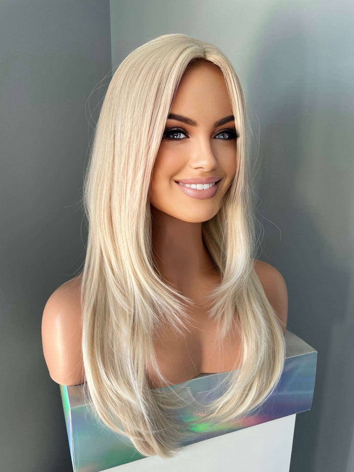 Blonde wig on a mannequin head with a plain background