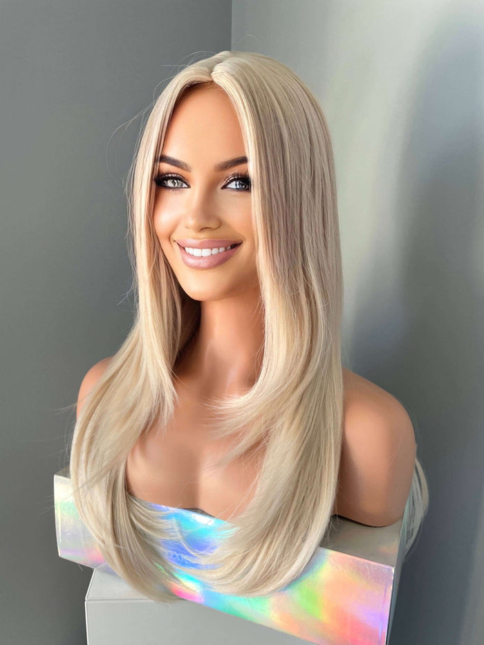 Blonde wig on a mannequin head against a gray background