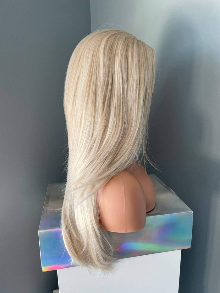 Blonde wig on a mannequin head against a plain background