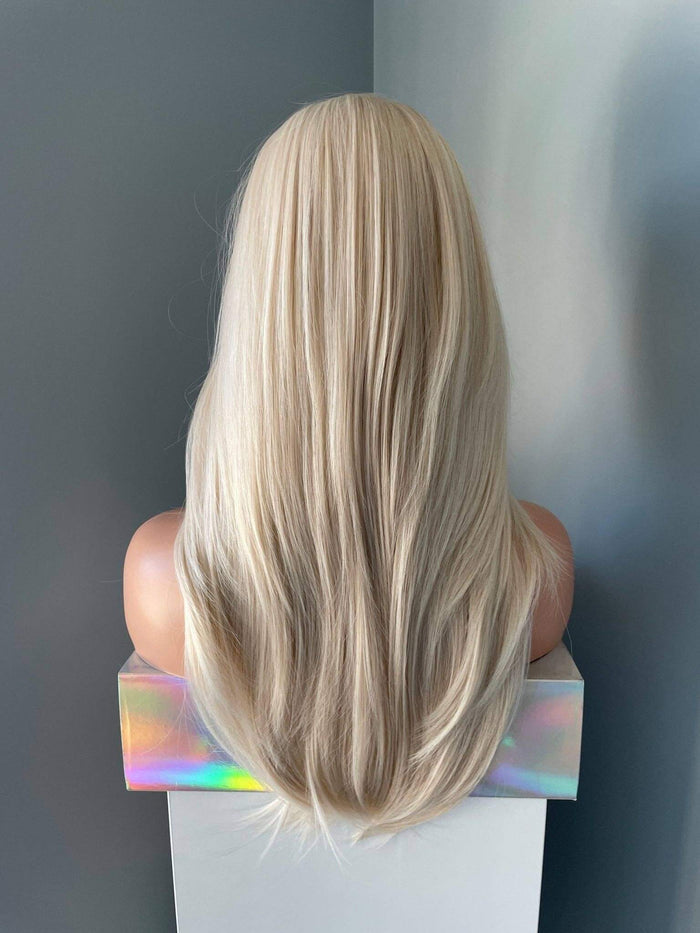 Blonde wig on a mannequin head against a gray background