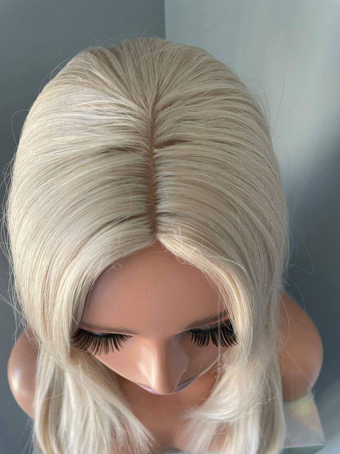 Blonde wig on a mannequin head against a neutral background