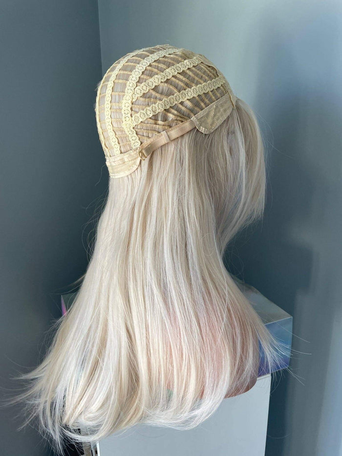 Blonde wig with a gold lace front on a mannequin head against a dark background