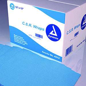 A box of light blue surgical drapes sits on a surface; some drapes are partially pulled out of the box. The box is labeled with a logo and what appears to be product information.