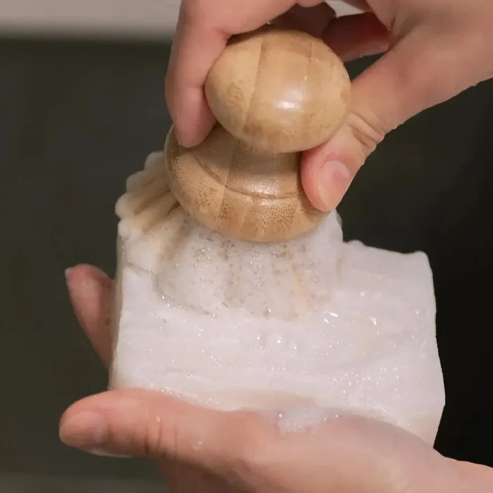 Person using a wooden pepper grinder on a white surface