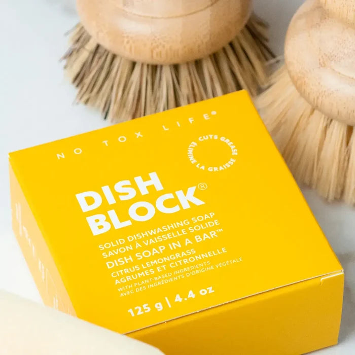 Yellow box of Dish Block solid dishwashing soap with brushes in the background