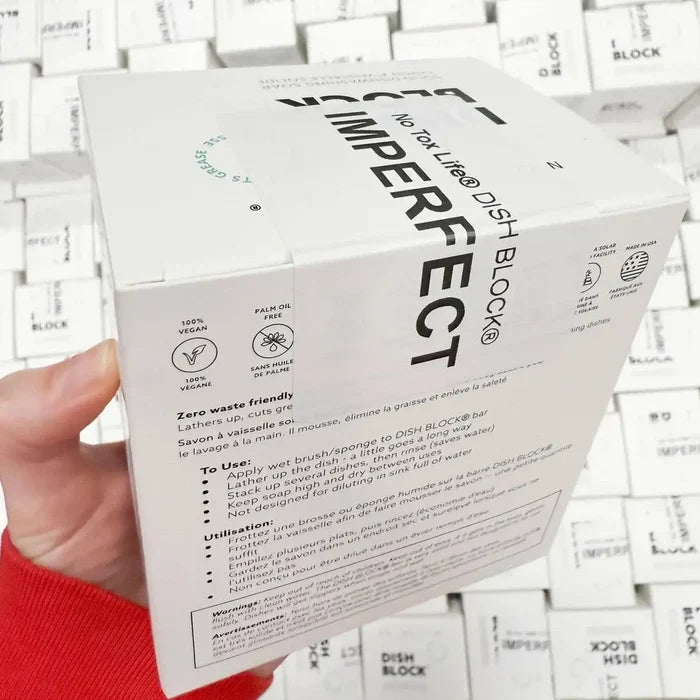 Hand holding a box of Dish Block Imperfect with white background