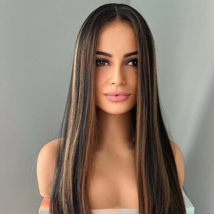 Woman with long, straight hair wearing a holographic top against a gray background
