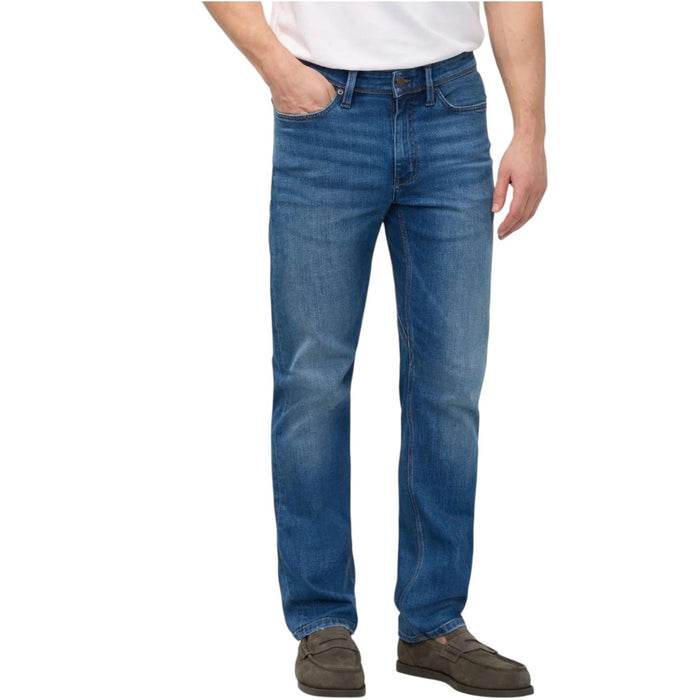 Close-up of a person wearing DUER’s PERFORMANCE DENIM+ Straight Pants in Alpine Indigo, showing relaxed hands and highlighting the texture, stitching, and stretch comfort of these blue jeans against a plain light background.