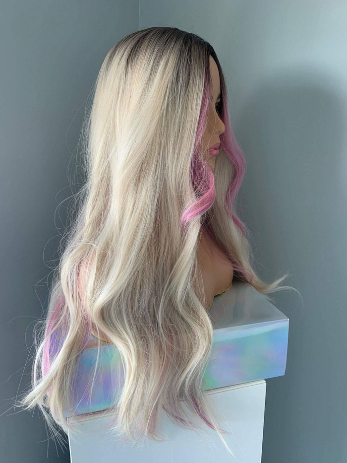 Mannequin head with long blonde and pink wig on a gray background