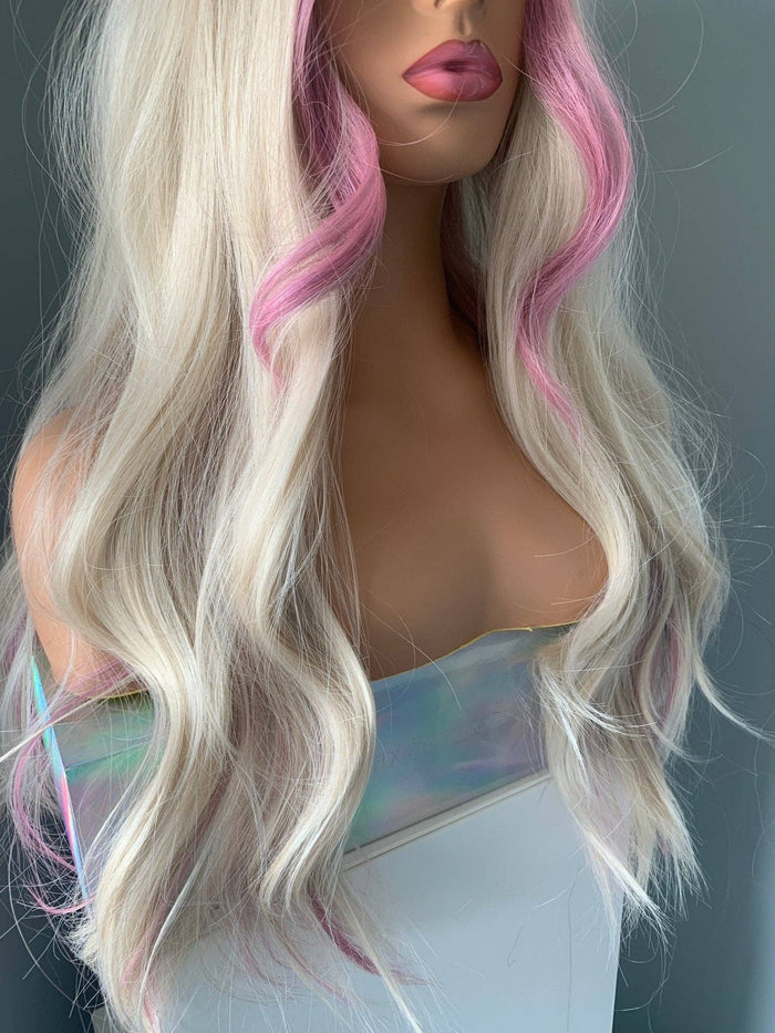 Mannequin head with long wavy hair transitioning from blonde to pink on a plain background