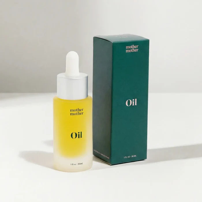 Yellow bottle and green box of 'mother mother' oil on a white background