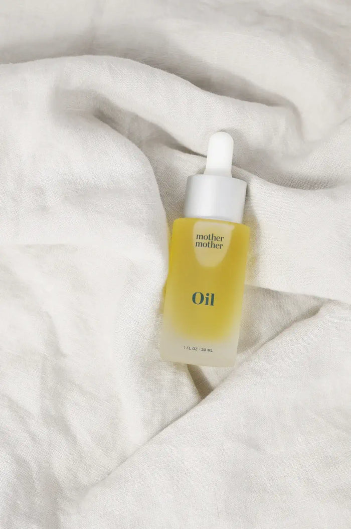 Skincare dropper bottle labeled 'Oil' on a textured white surface