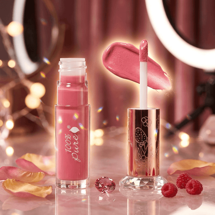 Pink lip gloss with applicator and '100% Pure' branding on a decorative background.