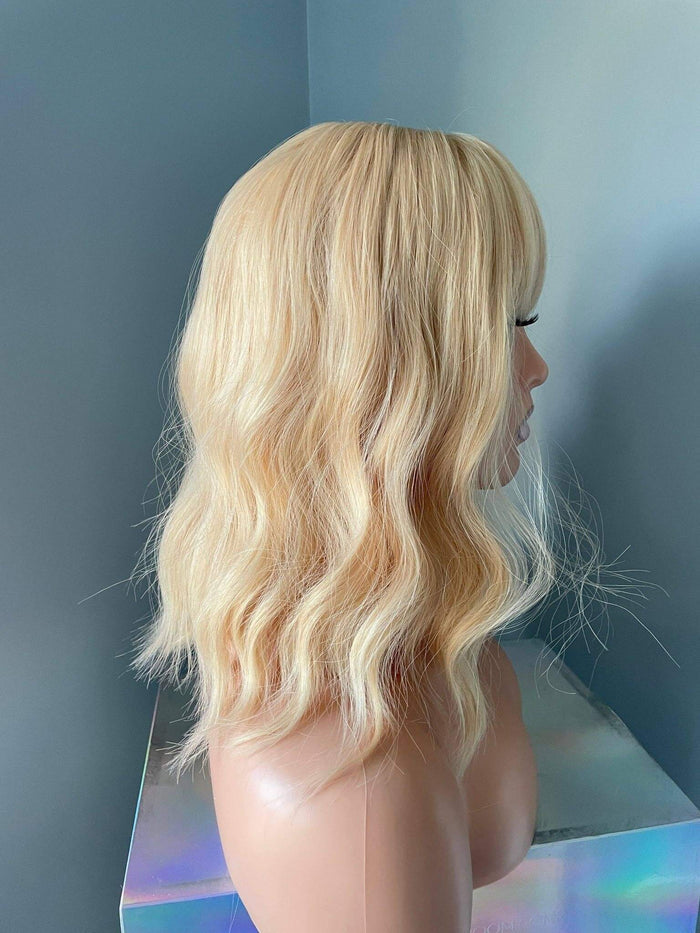 Blonde wig on a mannequin head against a plain background