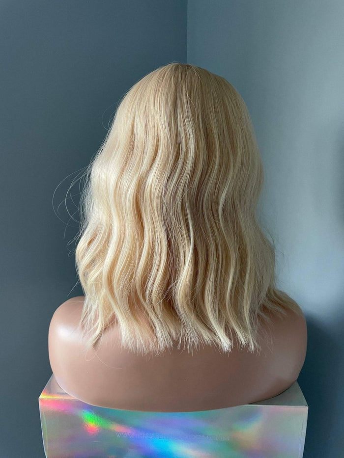 Blonde wig on a mannequin head against a plain background