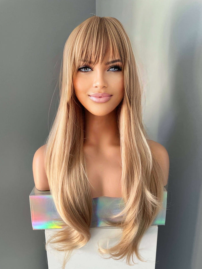Blonde wig with bangs on a mannequin head against a gray background