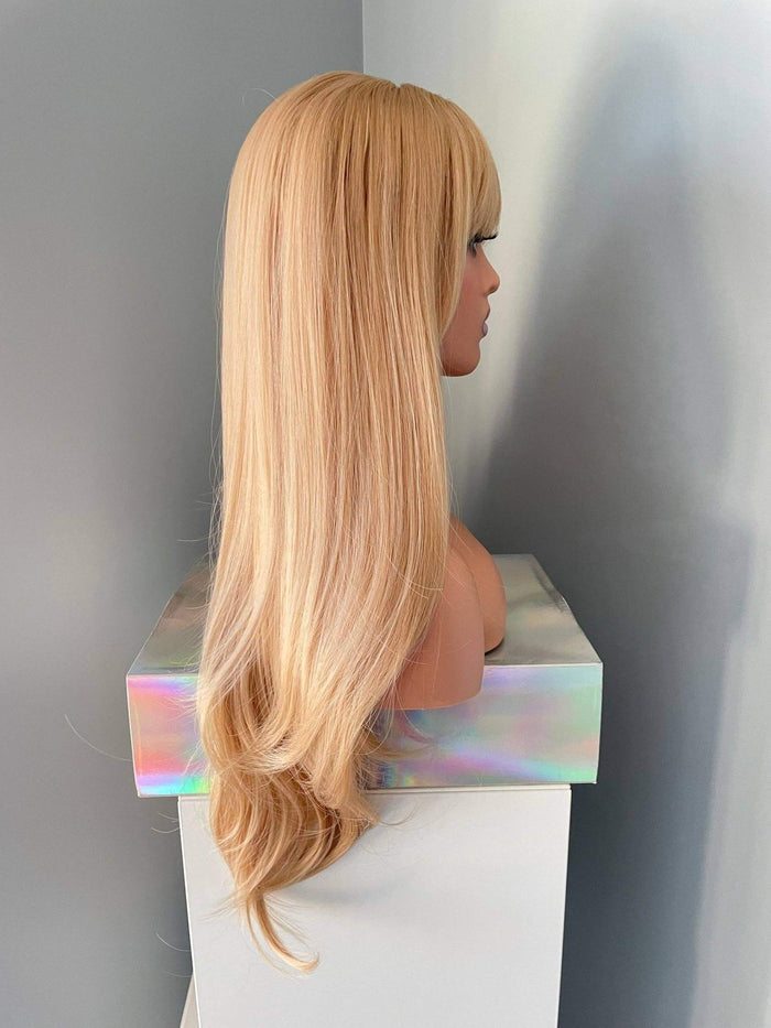 Blonde wig on a mannequin head against a plain background
