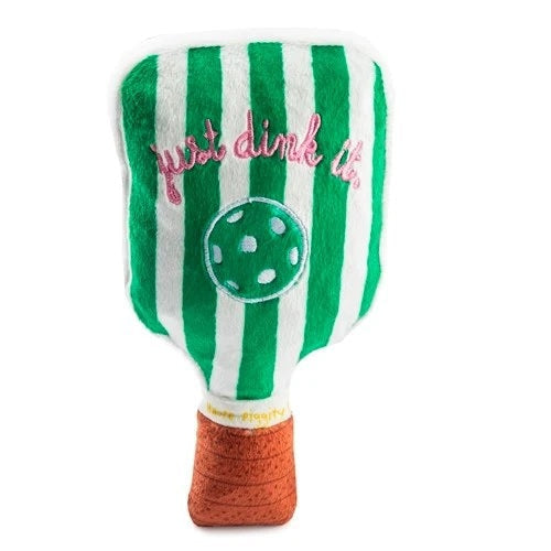 The HAUTE DIGGITY DOG GREEN STRIPED PICKLEBALL PADDLE DOG TOY is a squeaky plush toy shaped like a green pickleball paddle with a brown handle, featuring a white pickleball and "dink responsibly" embroidered on its surface—perfect for playful pups who love pickleball!.