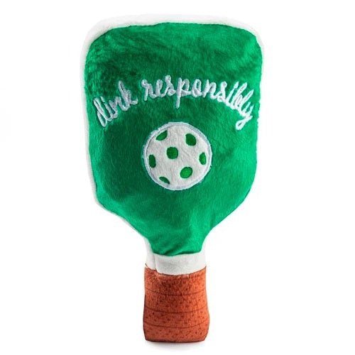 The HAUTE DIGGITY DOG GREEN STRIPED PICKLEBALL PADDLE DOG TOY is a plush squeaky dog toy shaped like a green and white striped pickleball paddle with a green ball in the center and "just dink it." embroidered in pink on the front, making it the perfect pickleball dog toy for playful pups.