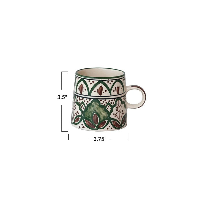 The CREATIVE COOP HAND-PAINTED STONEWARE MUG showcases a green and brown floral pattern with geometric and leaf motifs encircling its slightly flared body. This rustic mug features a comfortable handle and beautifully detailed decorative art, all carefully hand-painted on durable stoneware.