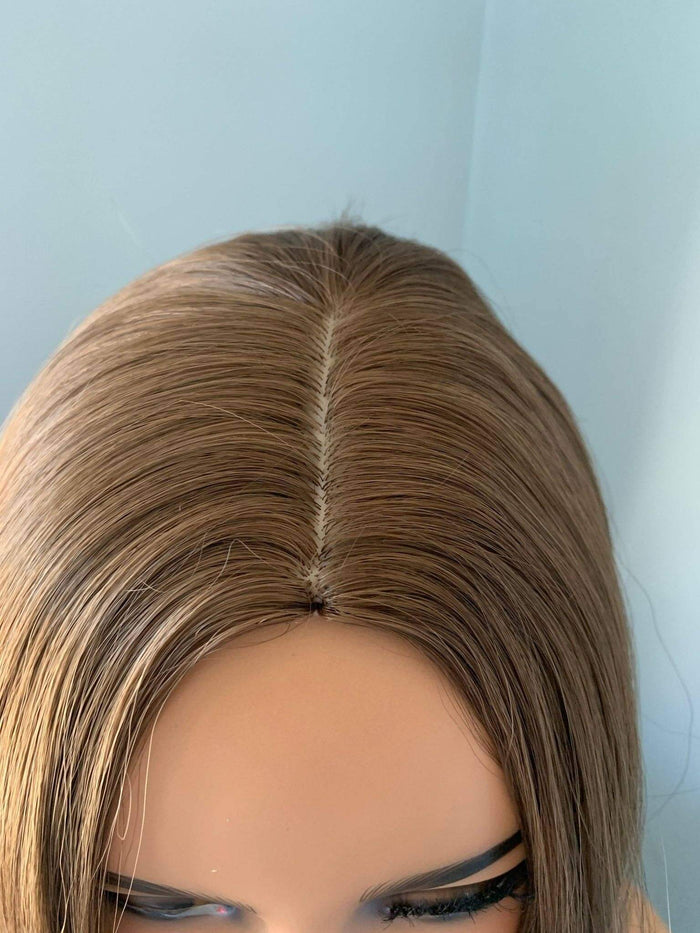 Close-up of a brown wig on a mannequin head against a light blue background