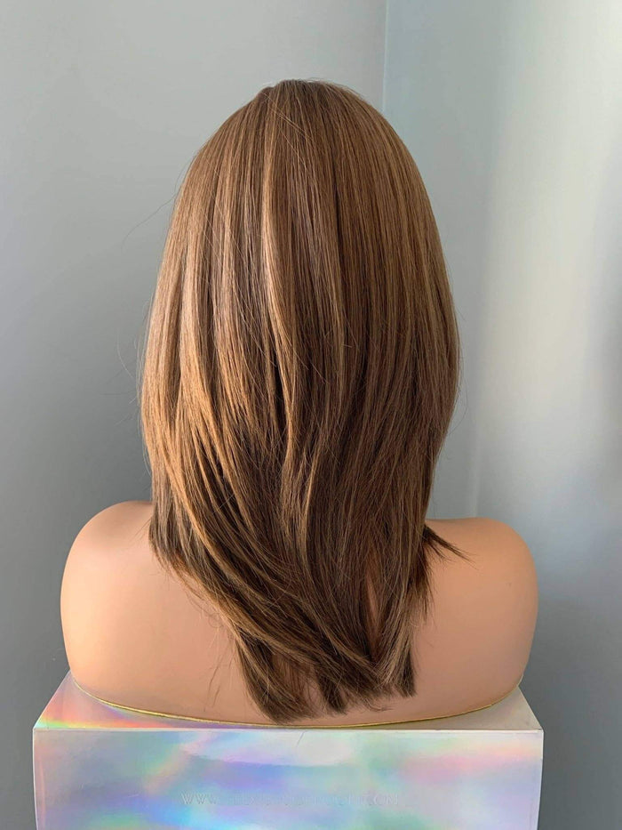 Brown wig on a mannequin head against a plain background