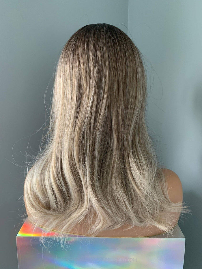 Harlow Rooted Ash Light Brown Wig with Bangs featuring soft, beachy waves and feathered curtain bangs from the back.