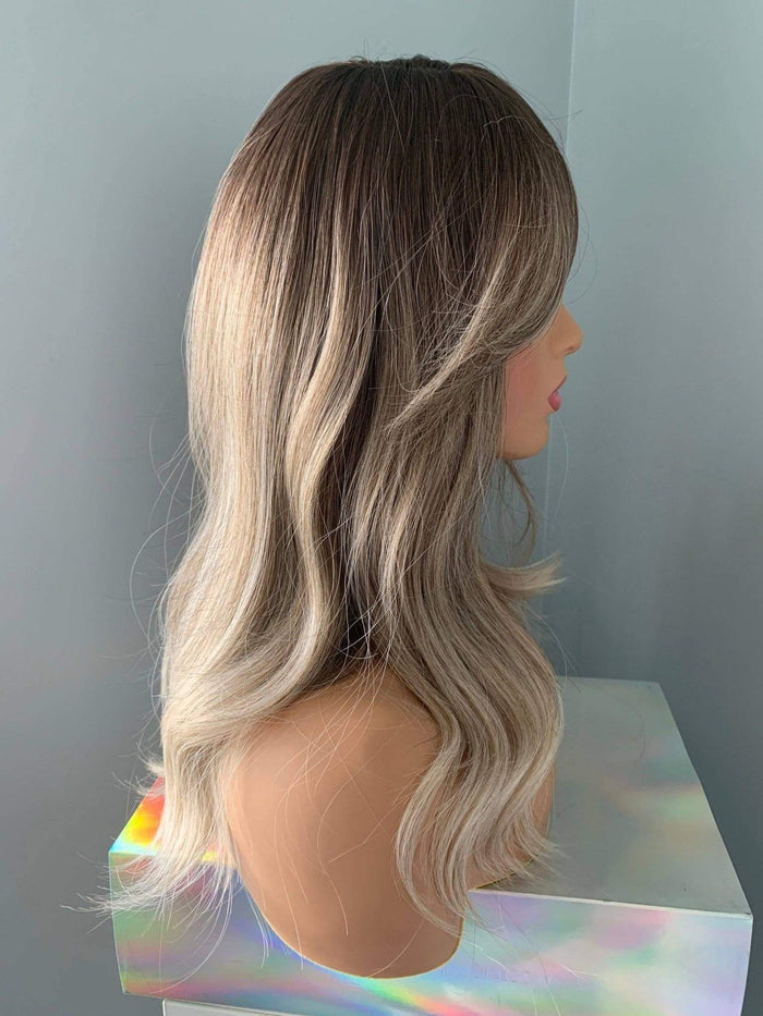 Harlow Rooted Ash Light Brown Wig with Bangs showcasing loose, beachy waves and modern feathered bangs.