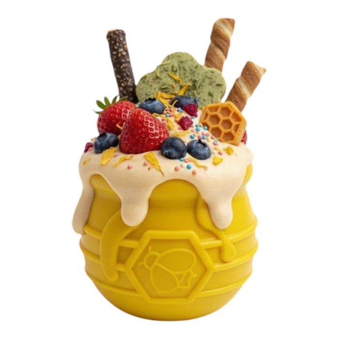 The SODA PUP HONEY POT DOG TREAT DISPENSER - YELLOW LARGE is a durable, barrel-shaped plastic enrichment toy for dogs, featuring a hexagonal pattern and a bee symbol on the side that mimics a honey pot. Shown against a plain white background, this puzzle feeder doubles as a treat dispenser to provide mental stimulation for your pup.