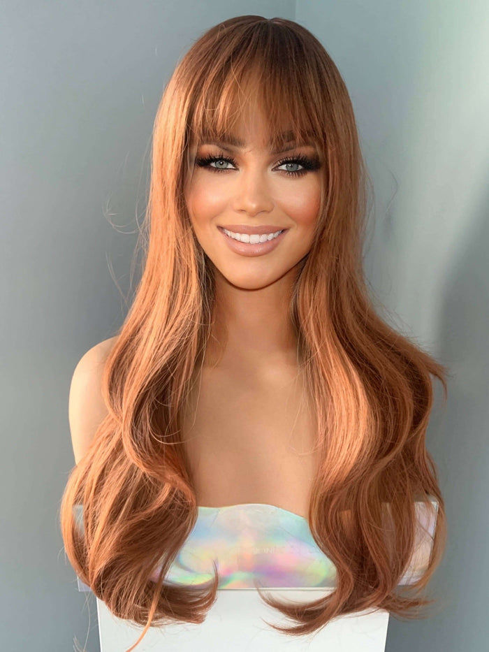 Jordan Auburn Wig with Bangs showcasing long wavy hair and a full fringe, perfect for glamorous looks.