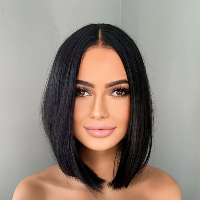 Woman with a stylish black bob haircut against a plain background