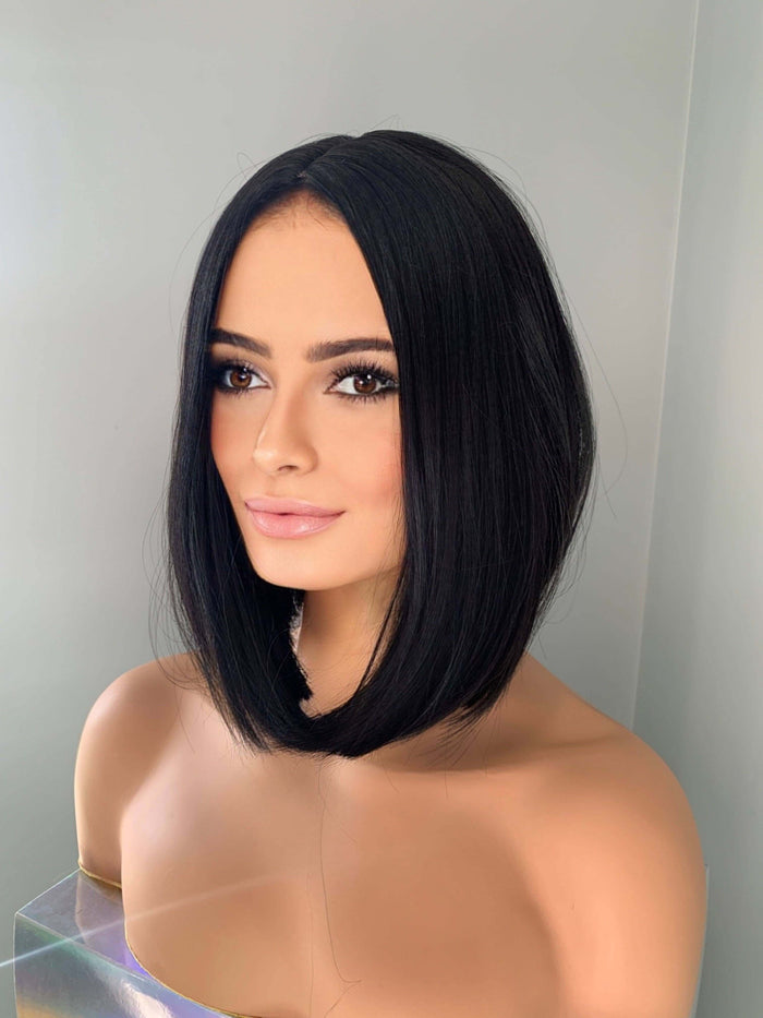 Black bob wig on a mannequin head against a plain background