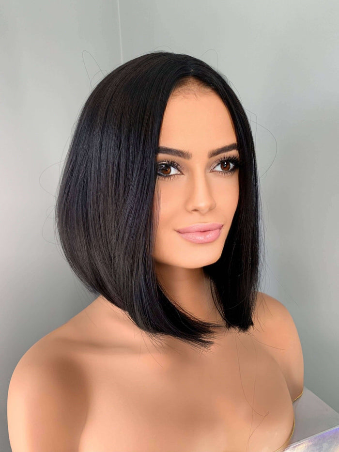 Person with a stylish black bob haircut against a plain background
