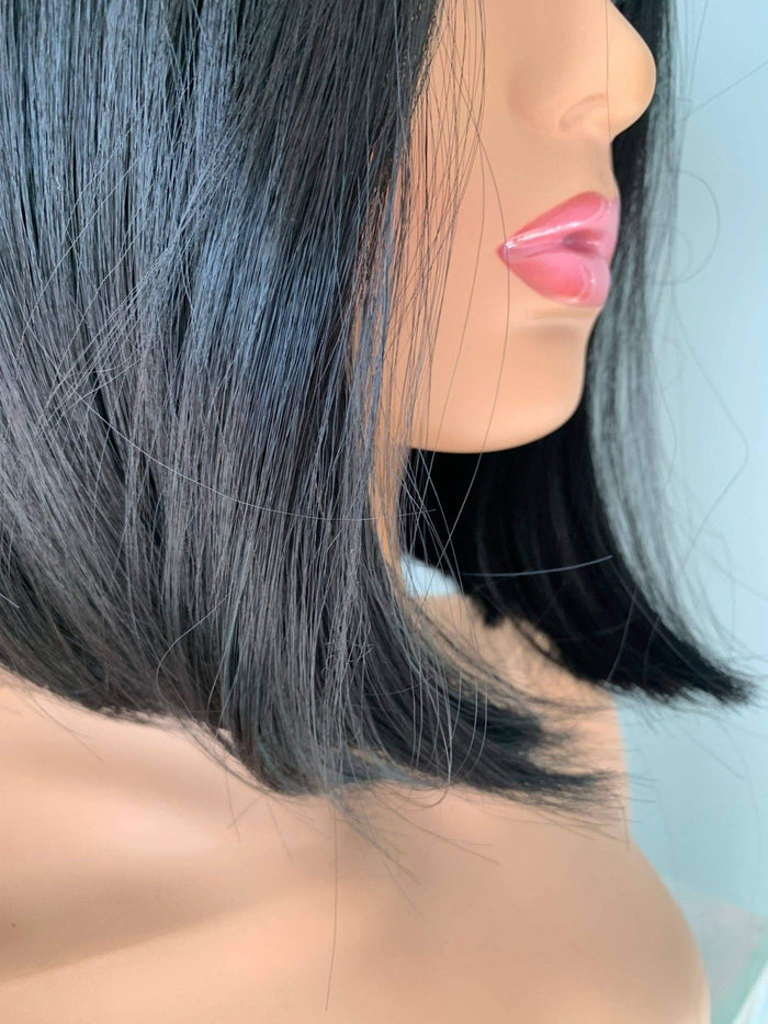 Mannequin head with black hair and pink lips against a light blue background