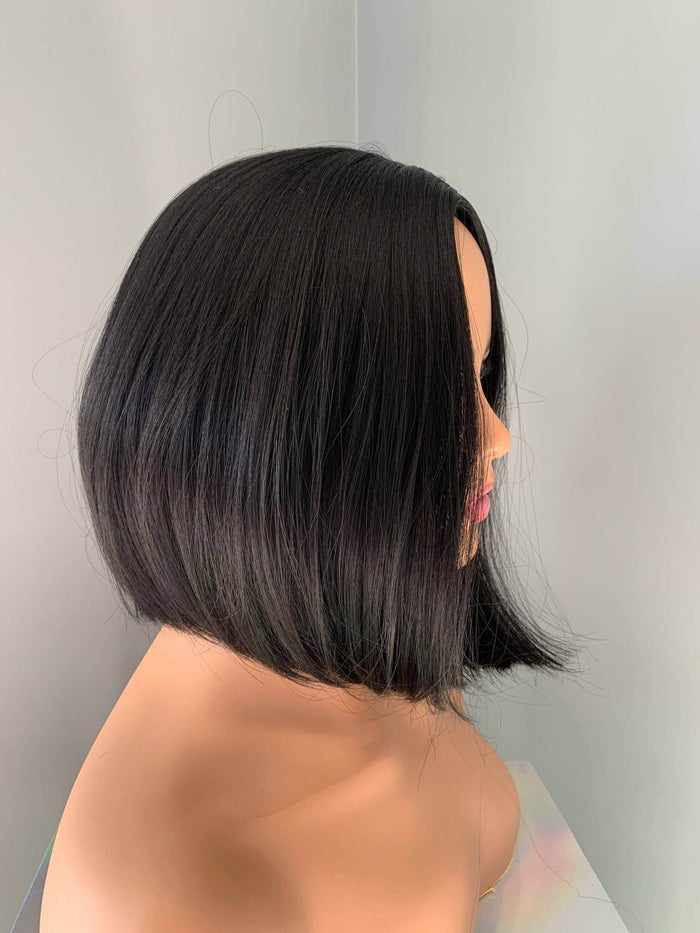 Person with a sleek, black bob haircut against a plain background
