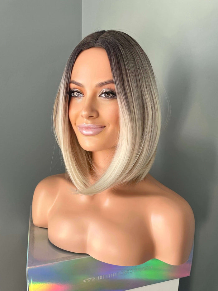 Katya Short Blonde Rooted Synthetic Bob Wig displayed on a mannequin, showcasing a chic and modern shoulder-length hairstyle.