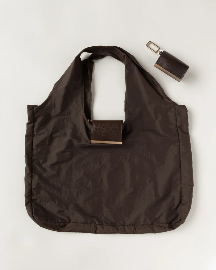 The KEOTE - KEYCHAIN TOTE IN ESPRESSO by KEOTE is a dark brown compact tote with two handles, featuring a detachable rectangular case in the center and an additional closed keychain tote, displayed on a light background.