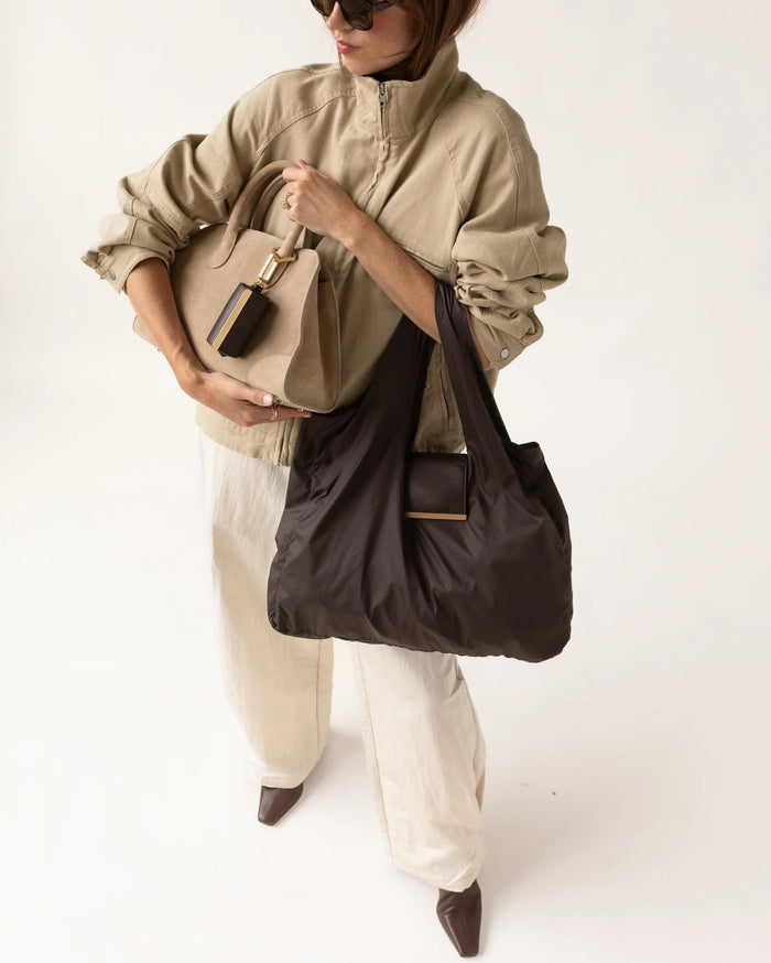 The KEOTE - KEYCHAIN TOTE IN ESPRESSO by KEOTE is a dark brown compact tote with two handles, featuring a detachable rectangular case in the center and an additional closed keychain tote, displayed on a light background.