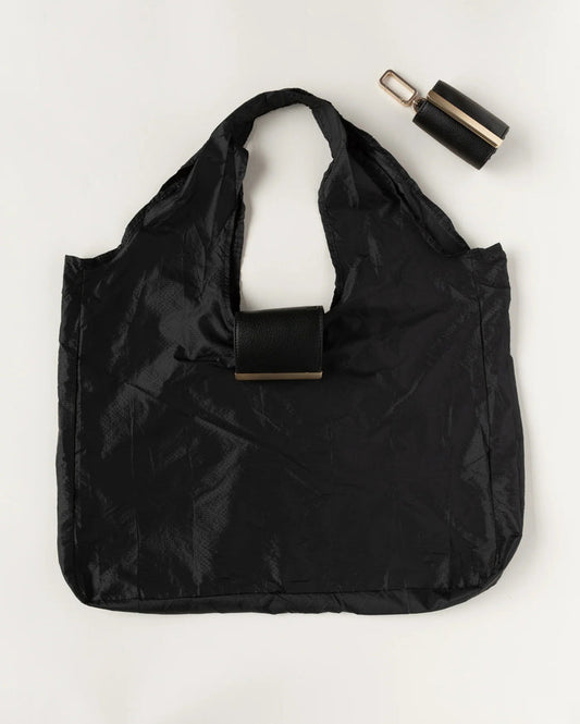 The KEOTE - KEYCHAIN TOTE IN JET BLACK by KEOTE is a reusable black tote made of crinkled fabric, shown flat with a matching small carrying case—ideal as a compact bag for easy storage and daily use.