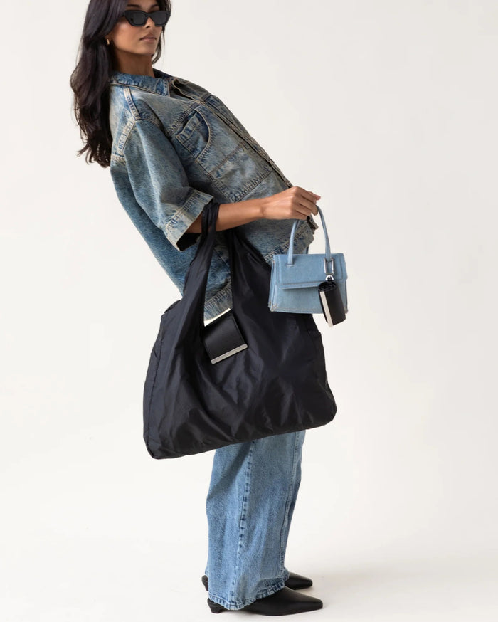 The KEOTE - KEYCHAIN TOTE IN JET BLACK by KEOTE is a reusable black tote made of crinkled fabric, shown flat with a matching small carrying case—ideal as a compact bag for easy storage and daily use.