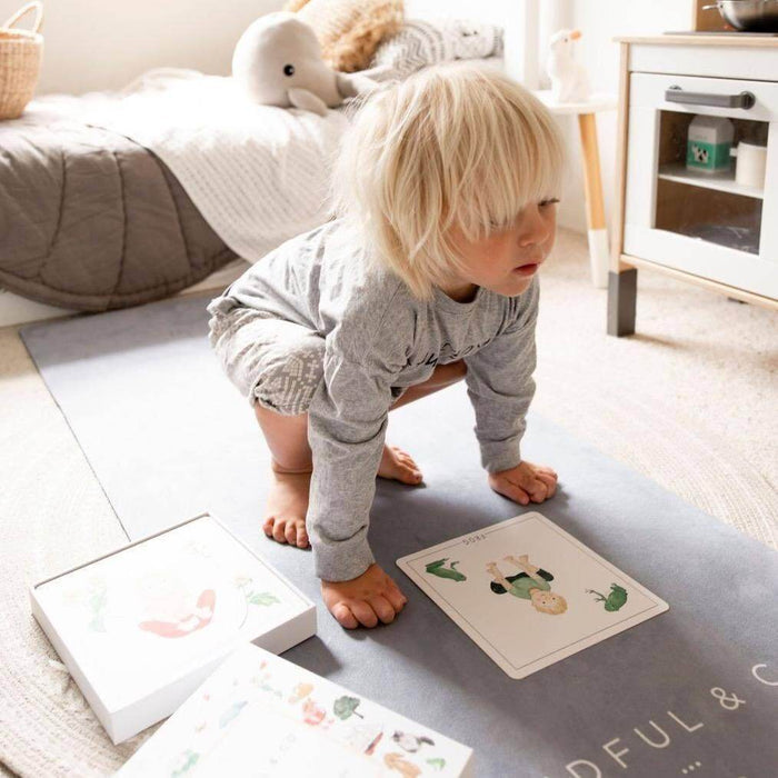 Child playing with educational cards on a mat in a room with toys and furniture.