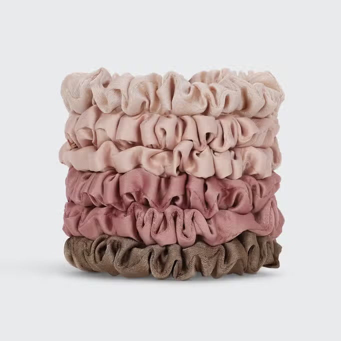 A set of six eco-friendly KITSCH - ULTRA PETITE SATIN SCRUNCHIES in elegant pink and beige shades is displayed on a branded card. These scrunchies not only enhance your style but also help reduce hair damage, making them both chic and gentle on your hair.