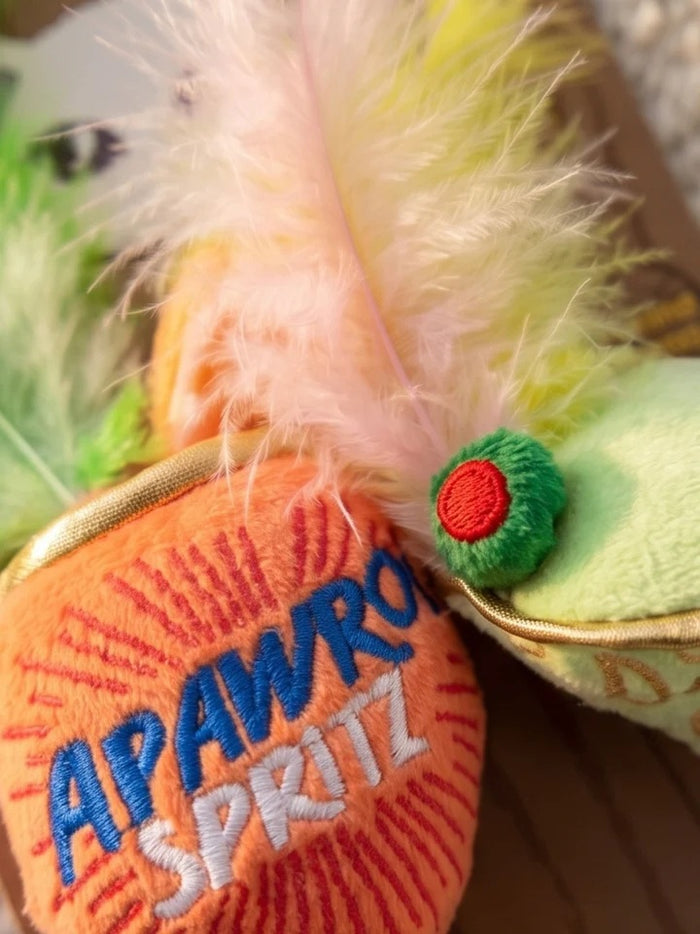 Delight and entertain your feline friend with the KITTY COCKTAILS ORGANIC CATNIP TOYS by HAUTE DIGGITY DOG—this playful set features two plush cat toys shaped like cocktails: one orange with a green feather, labeled "Apawrol Spritz," and one pale green with a yellow feather, labeled "Dirty Catini." Both toys have white stems, gold accents, and are crafted from organic catnip for irresistible feline fun.