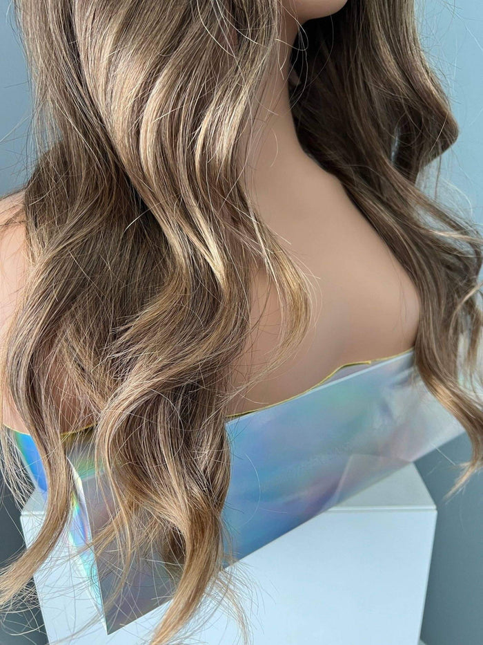 Close-up of the Kylie Long Brown Curled Wig showcasing soft, natural-looking curls against an iridescent background.