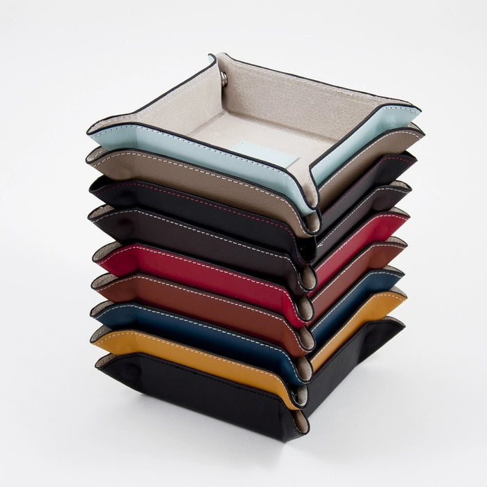 The BEYBERK INTERNATIONAL LEATHER SNAP VALET IN BLACK WITH RED STITCHING features raised, snap-secured corners and a central square stitched patch, serving as a stylish leather accessory organizer.