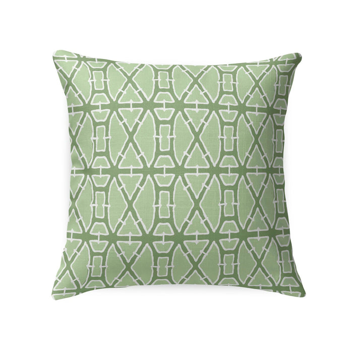 A woven rattan armchair features the LOOM & CLOTH Lattice Tailored Pillow in Green and sits beside a white nightstand with gold knobs, decorated with vases, against a blue wallpaper adorned with a gold leaf design.
