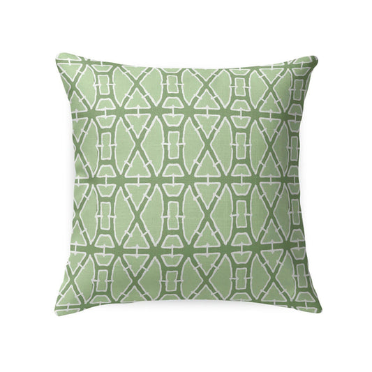 A woven rattan armchair features the LOOM & CLOTH Lattice Tailored Pillow in Green and sits beside a white nightstand with gold knobs, decorated with vases, against a blue wallpaper adorned with a gold leaf design.