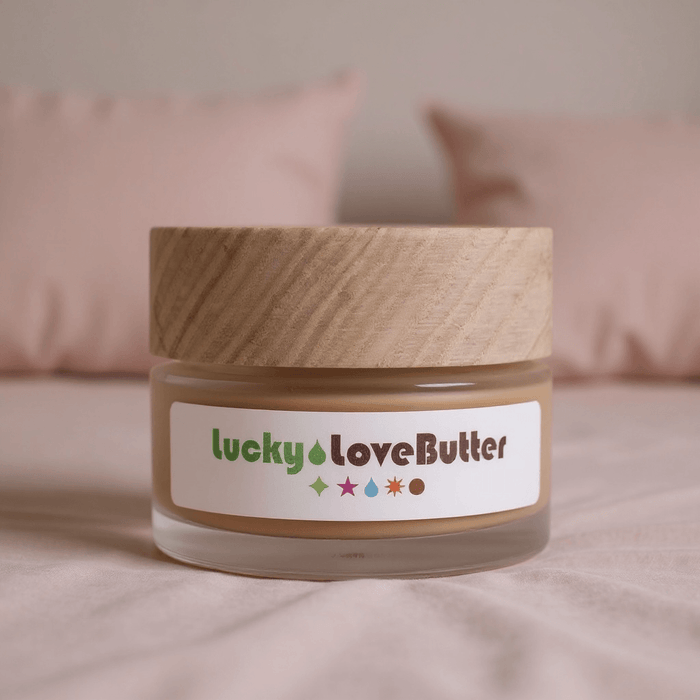 Jar of 'lucky love butter' with a wooden lid on a soft pink background