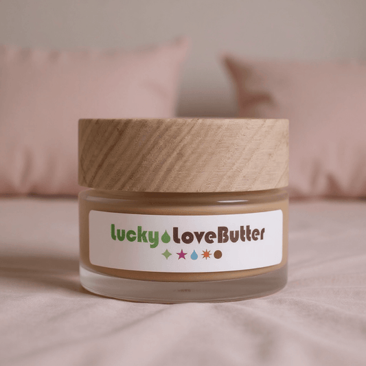 Jar of 'lucky love butter' with a wooden lid on a soft pink background