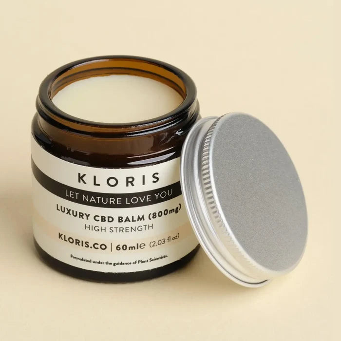 Jar of KLORIS CBD balm with a silver lid on a beige background